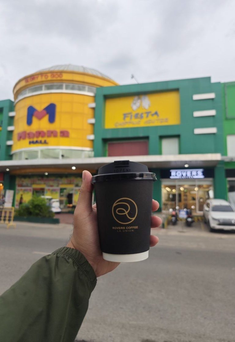 A person holding Rovers Cup in front of Rovers Coffee